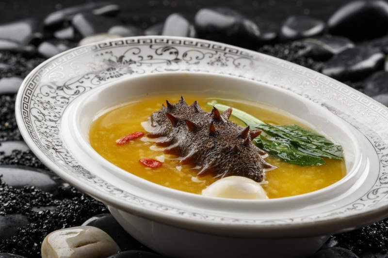 小米炖辽参摆放在黑色鹅卵石上图片