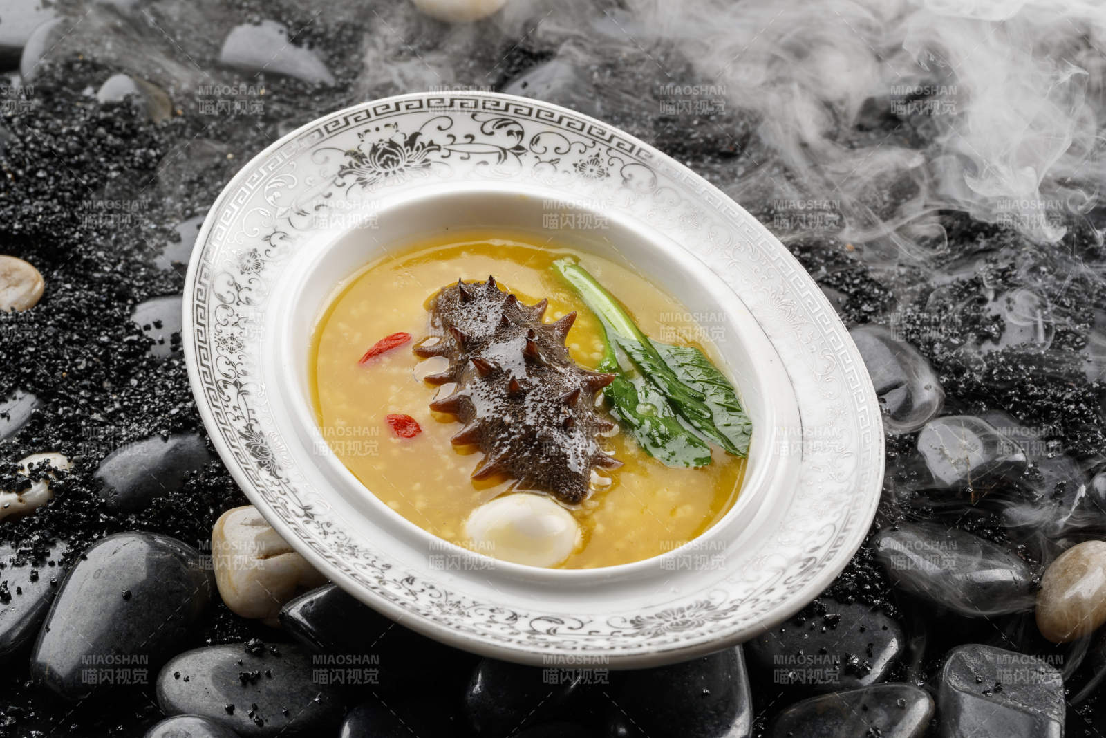 小米炖辽参摆放在黑色鹅卵石上图片