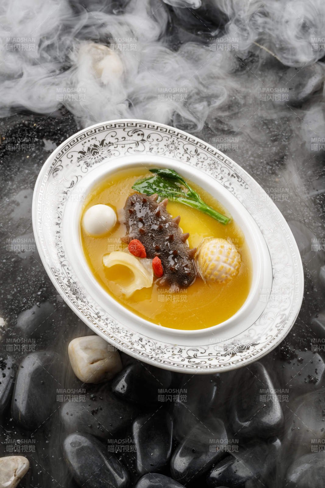 小米炖辽参摆放在黑色鹅卵石上图片