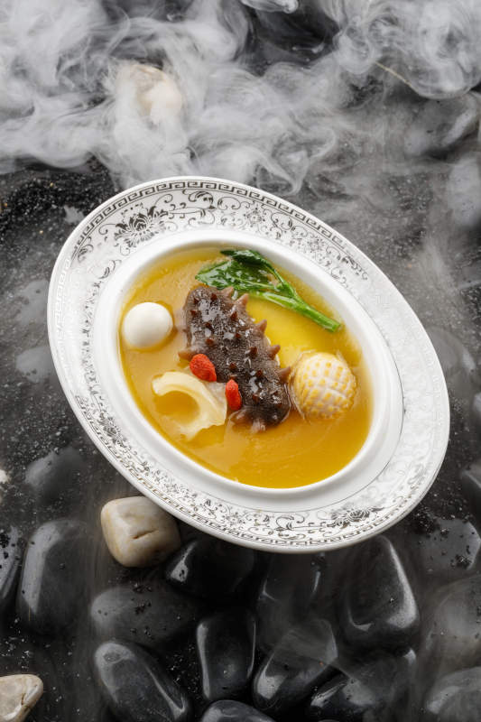 小米炖辽参摆放在黑色鹅卵石上图片