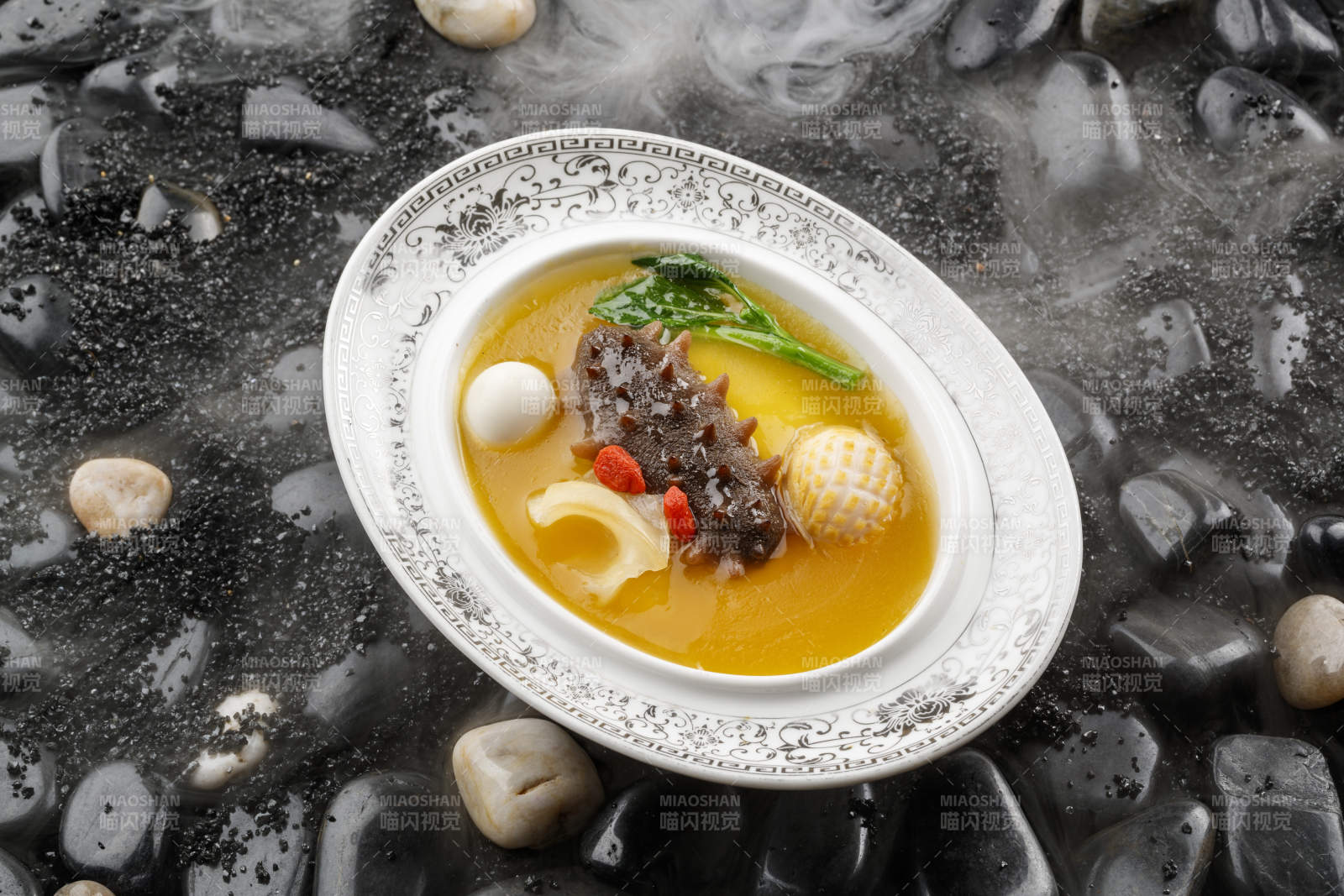 小米炖辽参摆放在黑色鹅卵石上图片