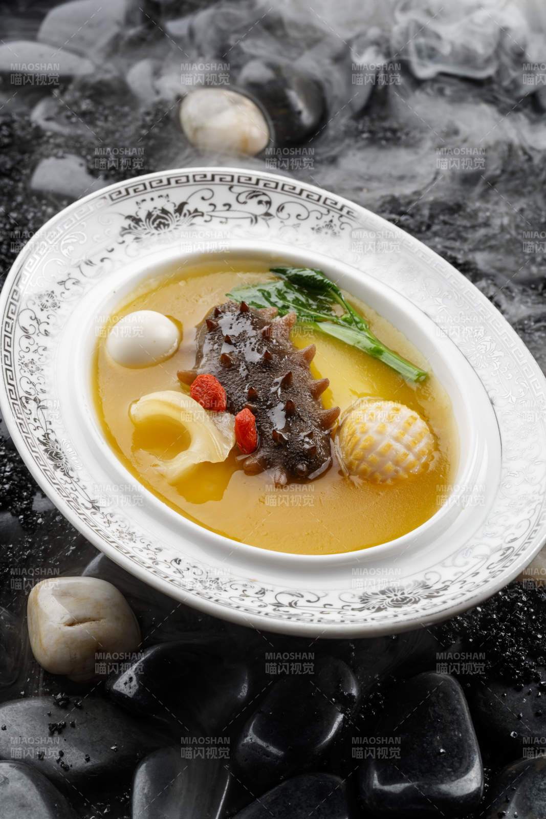 小米炖辽参摆放在黑色鹅卵石上图片