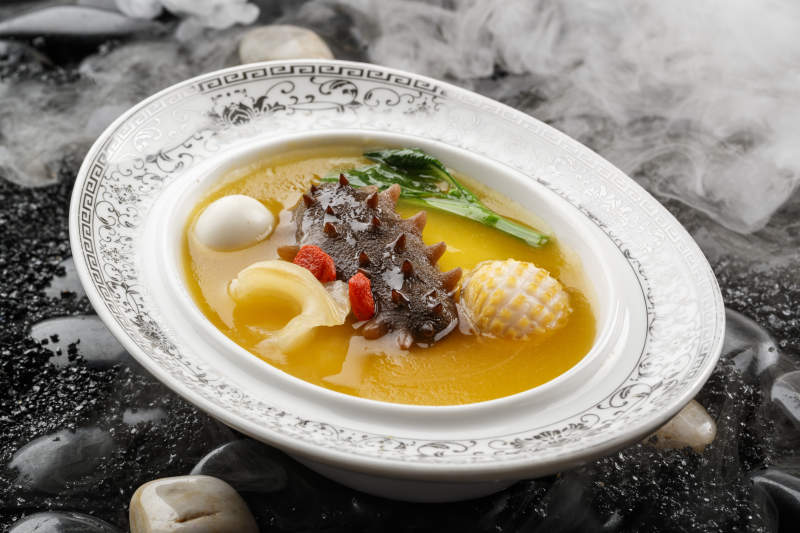 小米炖辽参摆放在黑色鹅卵石上图片