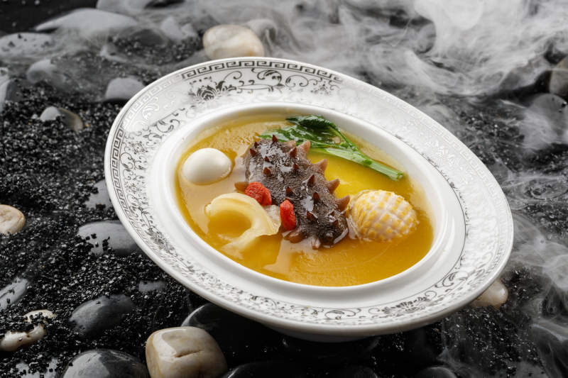 小米炖辽参摆放在黑色鹅卵石上图片