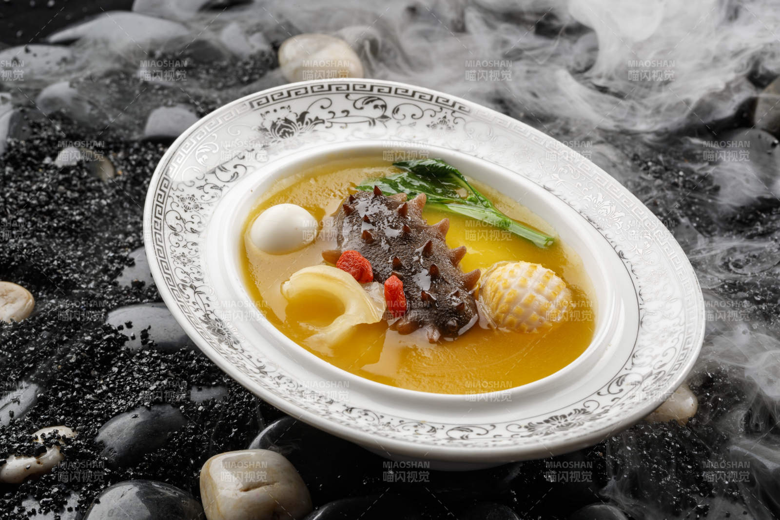 小米炖辽参摆放在黑色鹅卵石上图片