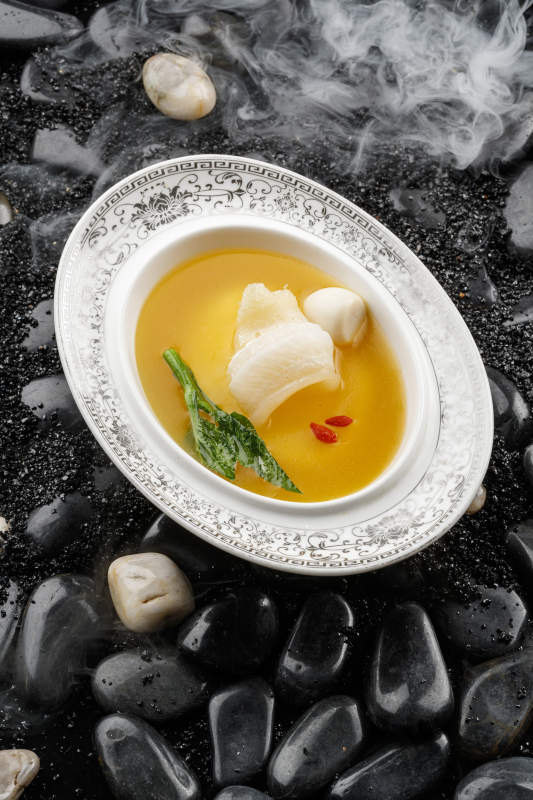 浓汤鱼唇摆放在干冰缭绕的鹅卵石上图片