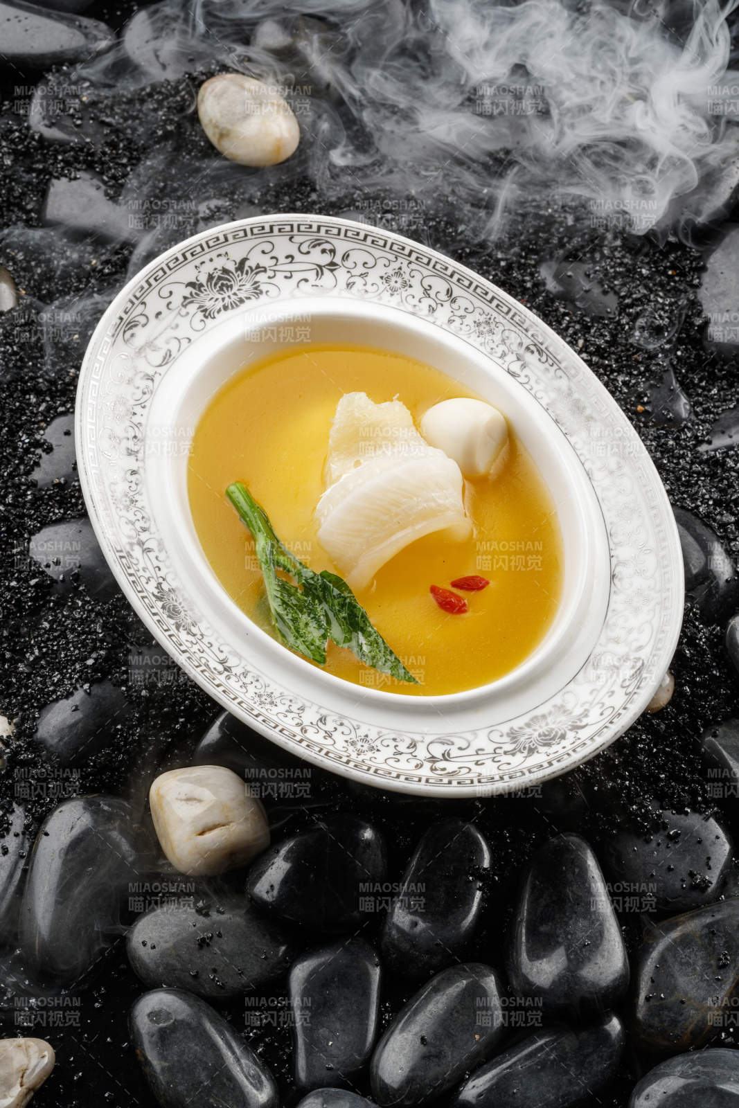 浓汤鱼唇摆放在干冰缭绕的鹅卵石上图片