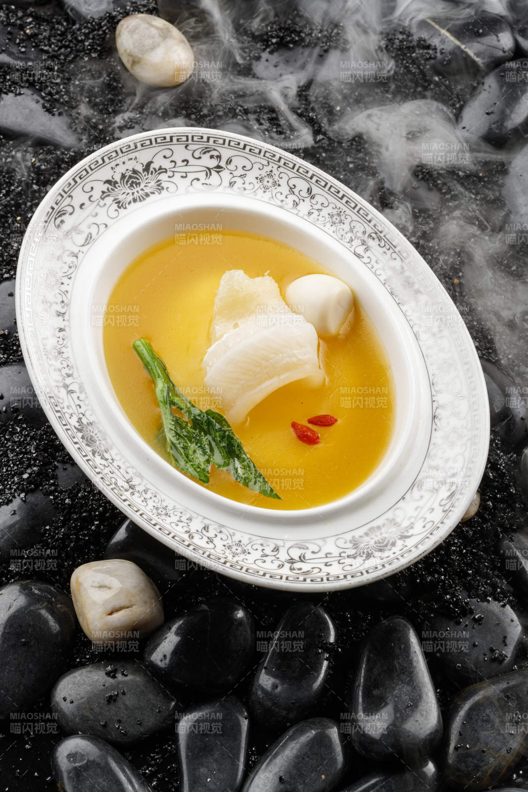 浓汤鱼唇摆放在干冰缭绕的鹅卵石上图片
