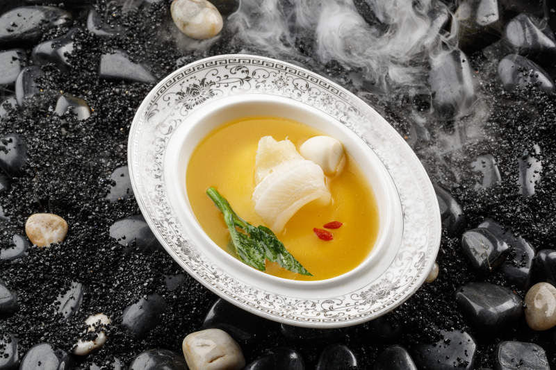 浓汤鱼唇摆放在干冰缭绕的鹅卵石上图片