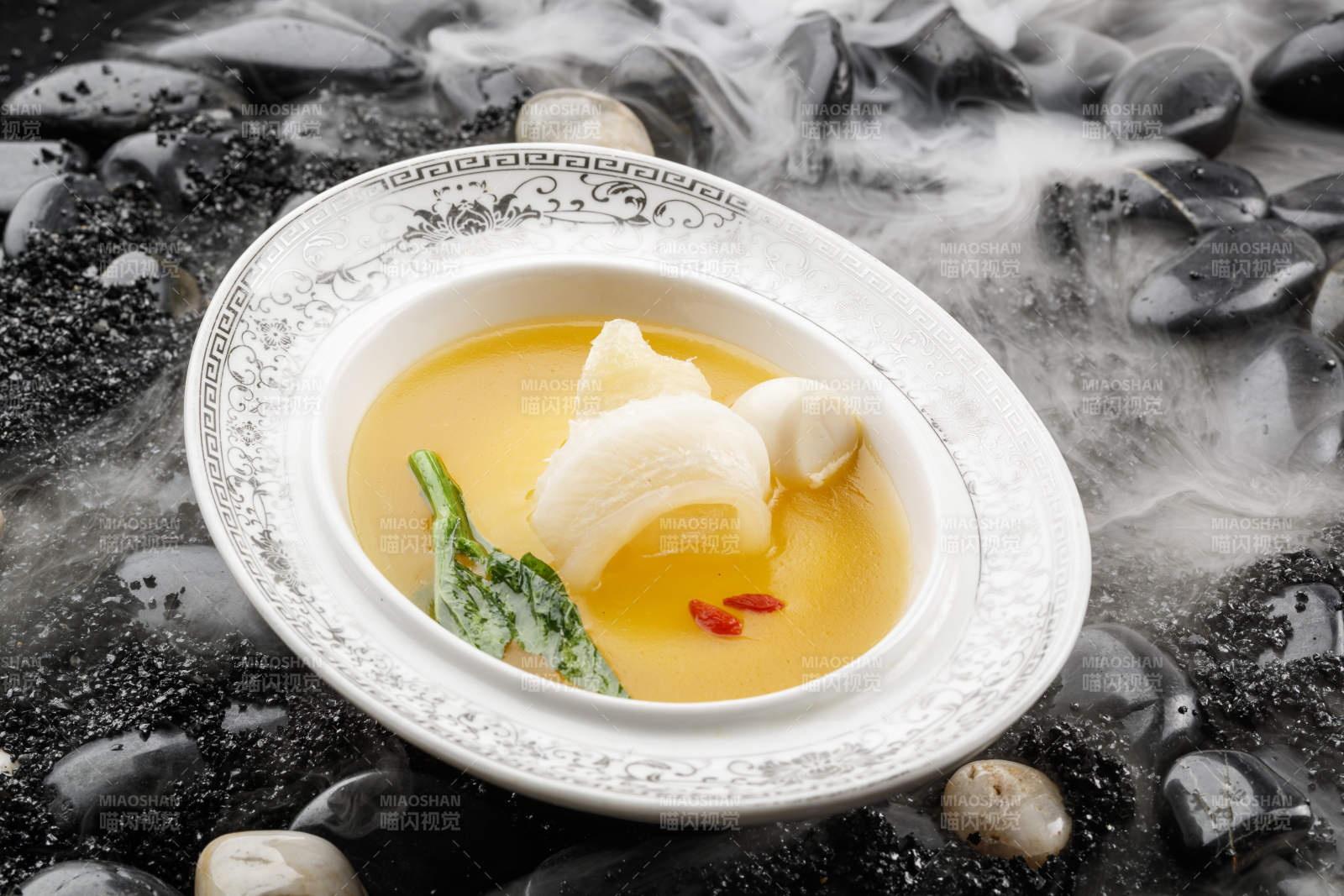 浓汤鱼唇摆放在干冰缭绕的鹅卵石上图片