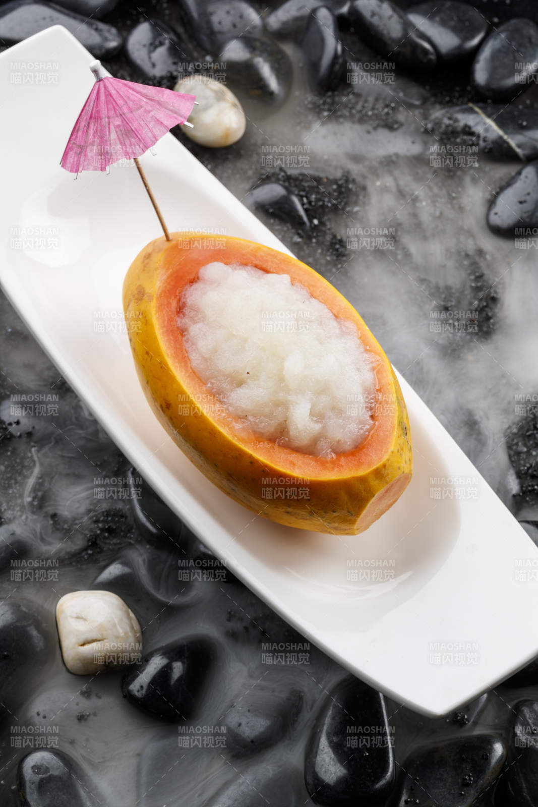 木瓜炖雪蛤摆放在干冰缭绕的鹅卵石上图片