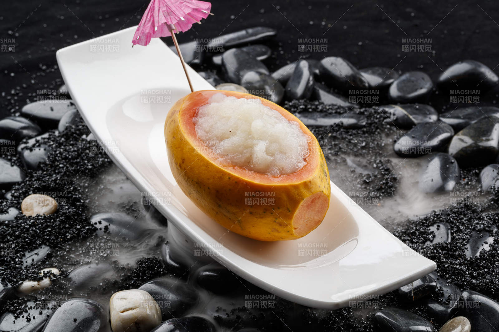 木瓜炖雪蛤摆放在干冰缭绕的鹅卵石上图片