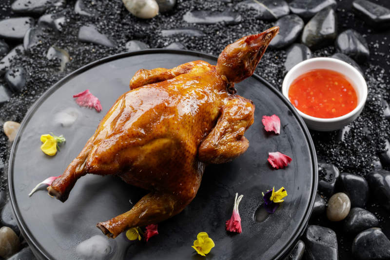 黑色底盘装的港式脆皮鸡摆放在黑色鹅卵石上图片