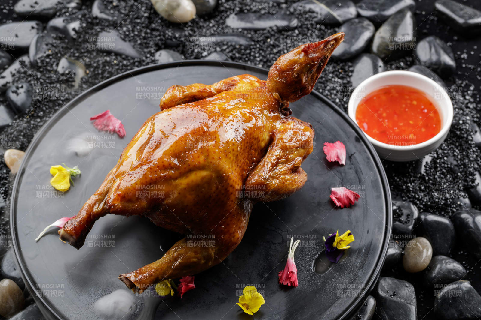 黑色底盘装的港式脆皮鸡摆放在黑色鹅卵石上图片
