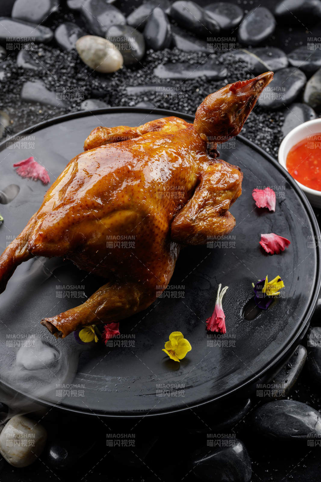 黑色底盘装的港式脆皮鸡摆放在黑色鹅卵石上图片