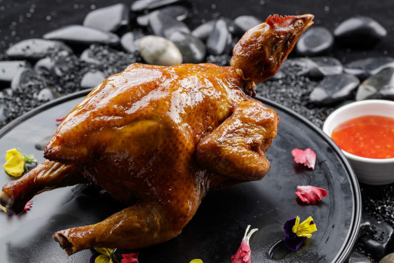 黑色底盘装的港式脆皮鸡摆放在黑色鹅卵石上图片