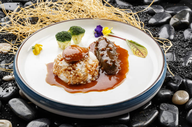 鲜鲍鱼辽参捞饭摆放在黑色鹅卵石上图片