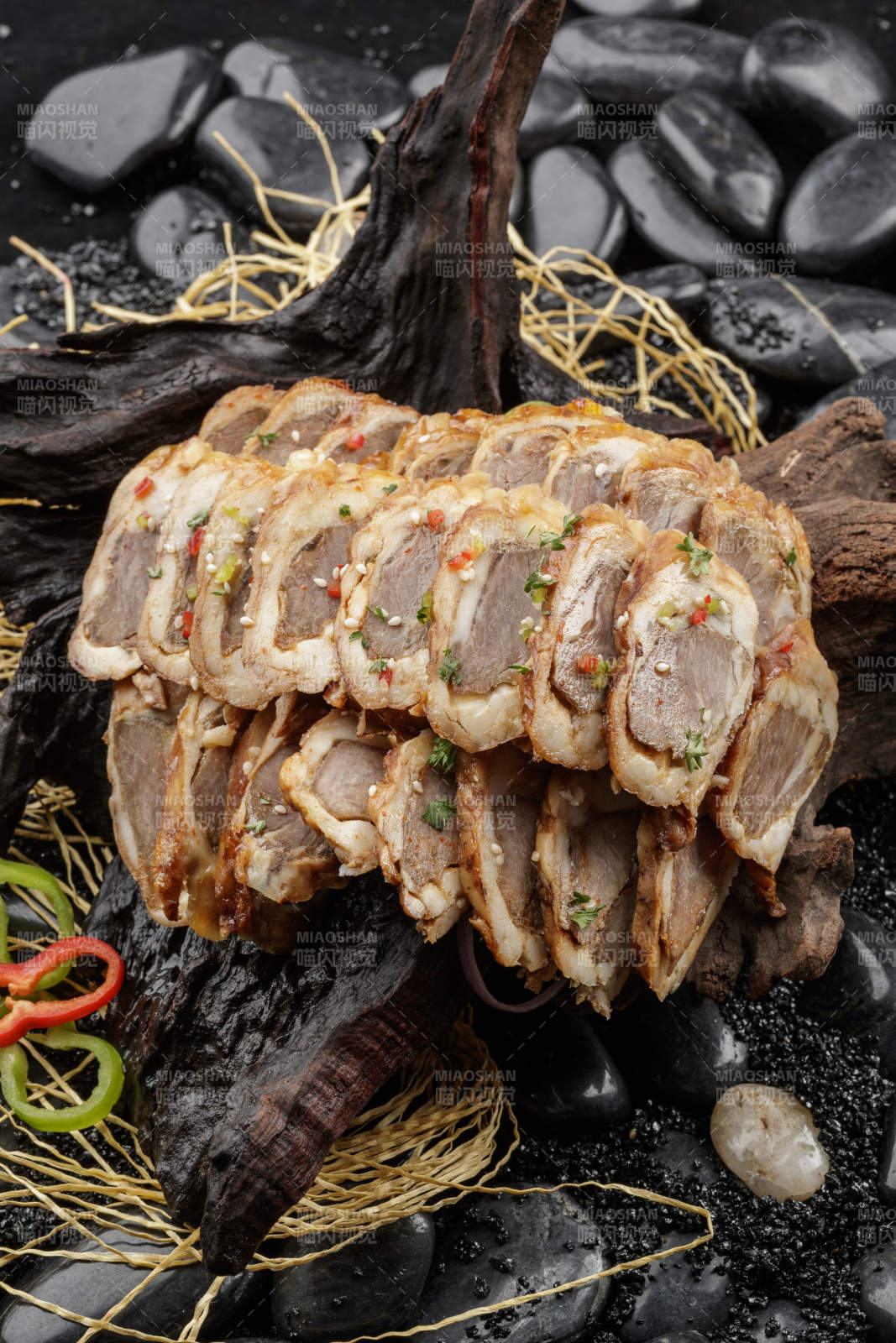 崖柏根装的蒙古烤羊里脊摆放在黑色鹅卵石上图片