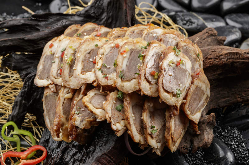 崖柏根装的蒙古烤羊里脊摆放在黑色鹅卵石上图片