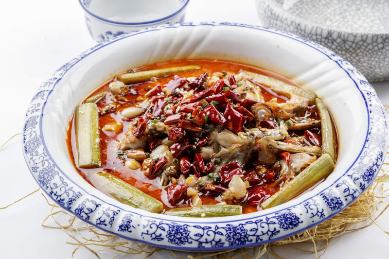 青花瓷盘装的湘味馋嘴蛙摆放在白色底板上图片