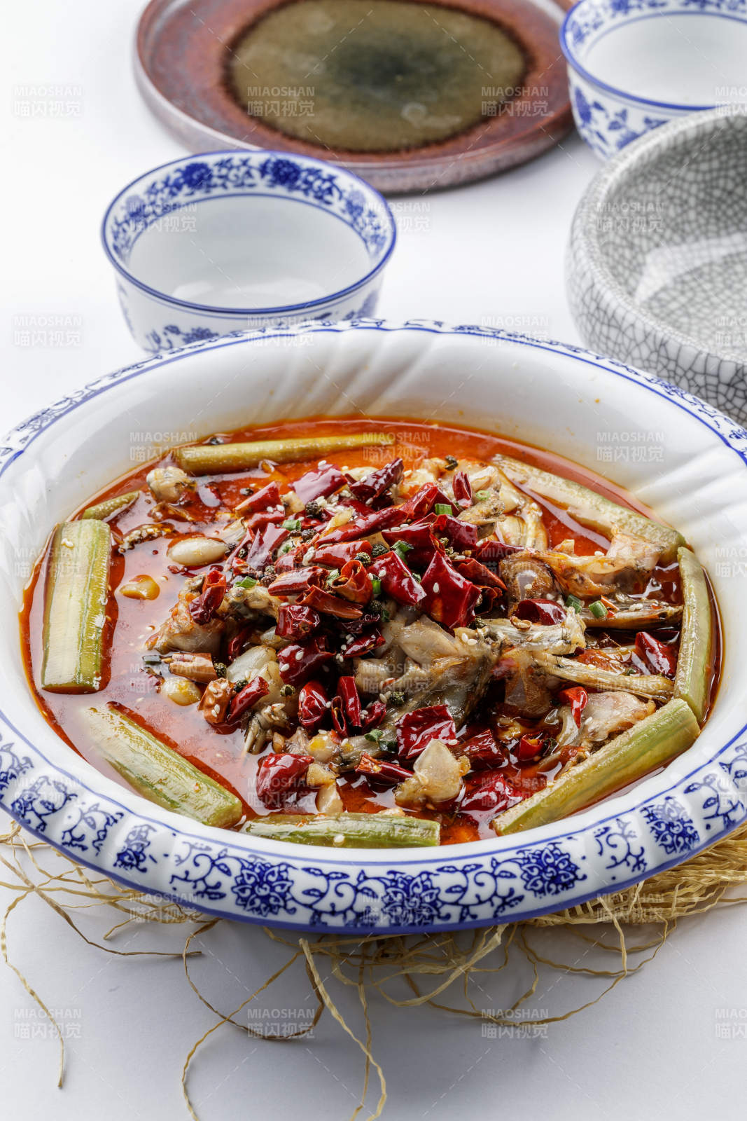 青花瓷盘装的湘味馋嘴蛙摆放在白色底板上图片