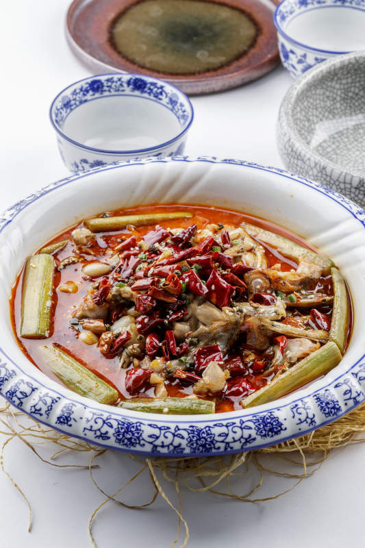 青花瓷盘装的湘味馋嘴蛙摆放在白色底板上图片