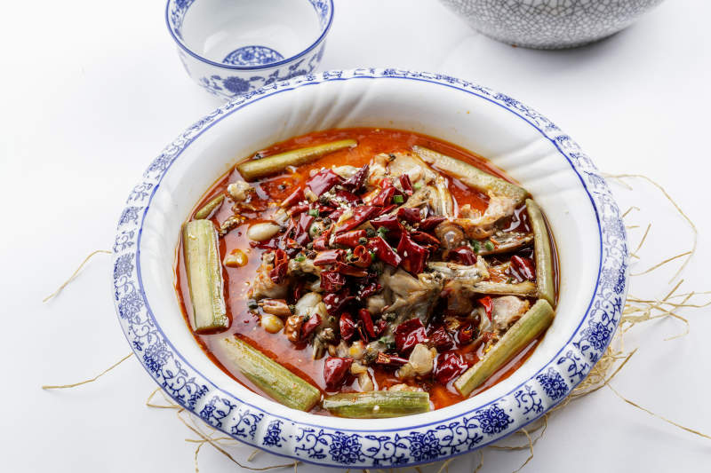 青花瓷盘装的湘味馋嘴蛙摆放在白色底板上图片