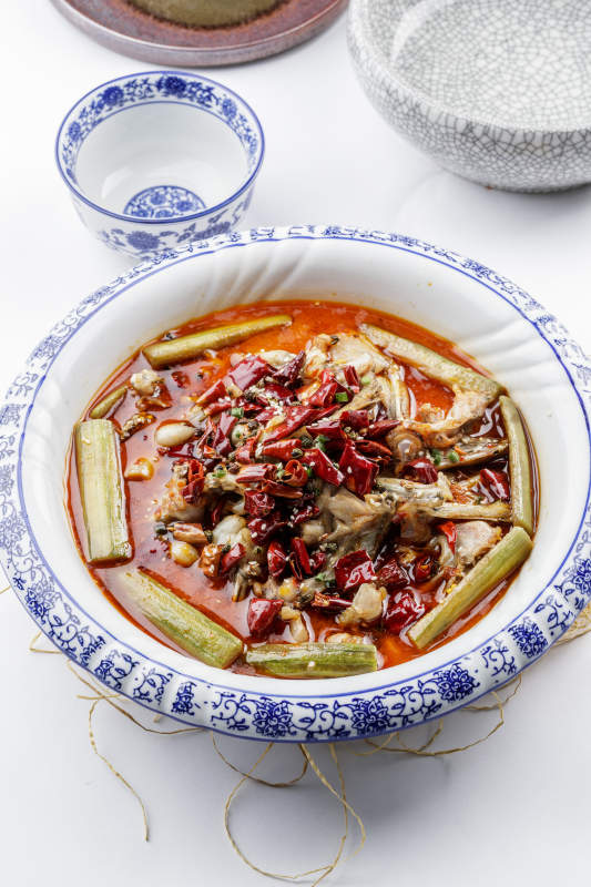 青花瓷盘装的湘味馋嘴蛙摆放在白色底板上图片