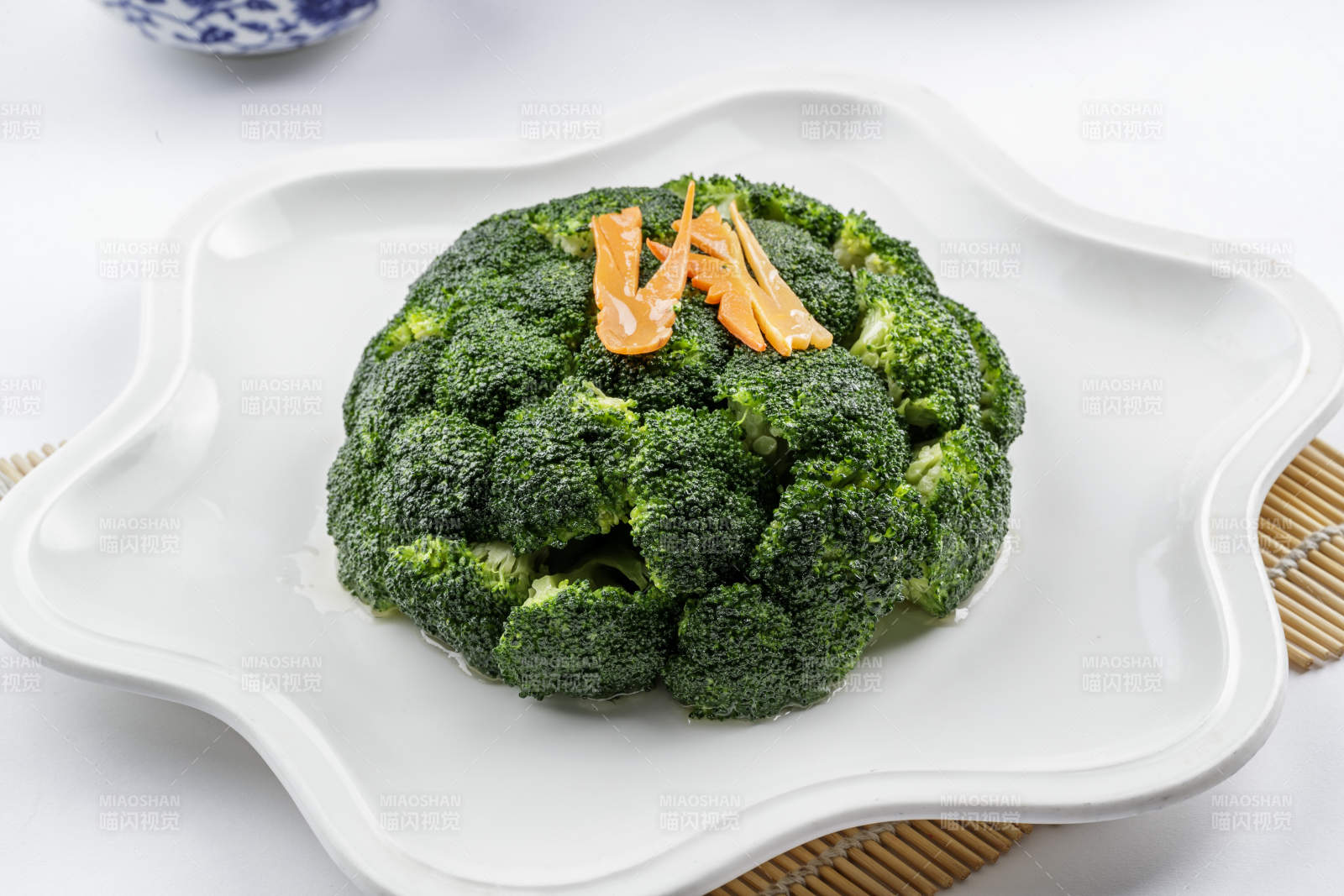 白色梅花瓷盘装的白灼西蓝花摆放在寿司帘上图片