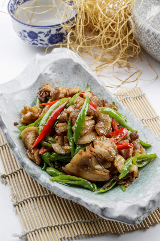 青瓷盘装的湘味小炒肉摆放在寿司帘上图片