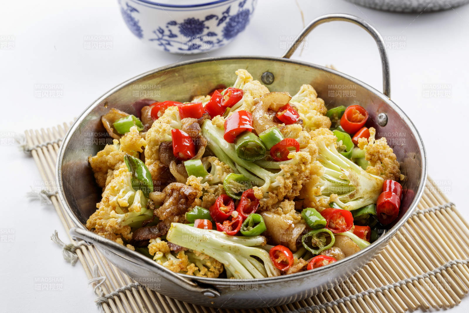 铁锅装的小炒有机菜花摆放在寿司帘上图片