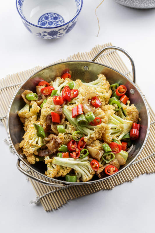 铁锅装的小炒有机菜花摆放在寿司帘上图片