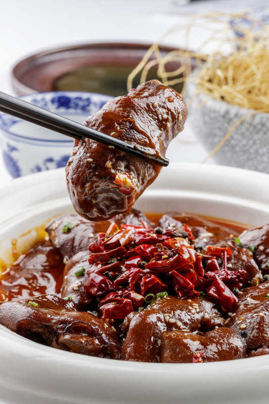 白色圆盘装的香辣猪蹄摆放在白色背景上图片