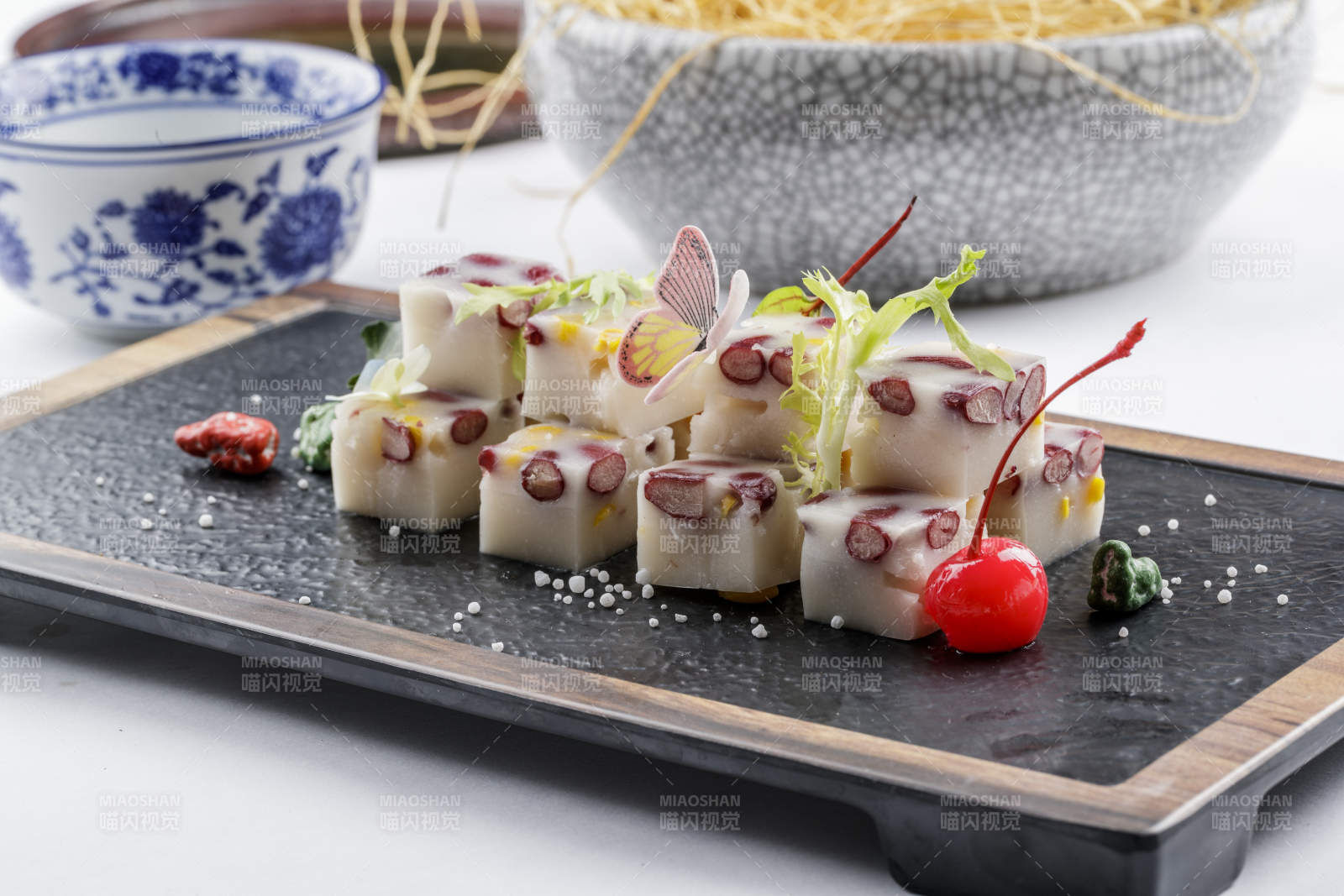 黑色石盘装的酸奶红豆糕摆放在白色背景上图片