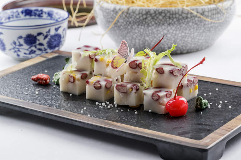 黑色石盘装的酸奶红豆糕摆放在白色背景上图片