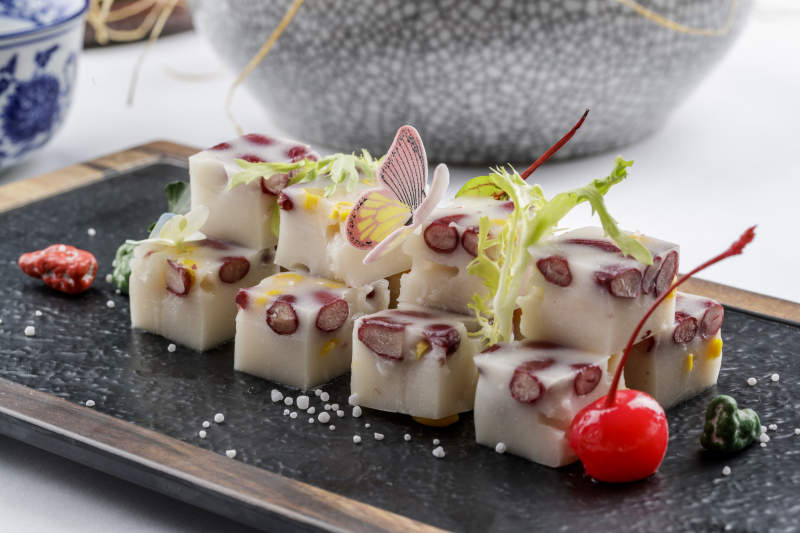 黑色石盘装的酸奶红豆糕摆放在白色背景上图片