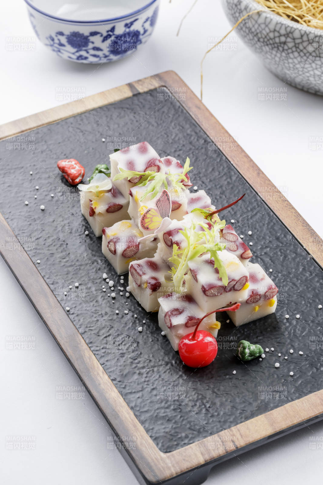 黑色石盘装的酸奶红豆糕摆放在白色背景上图片