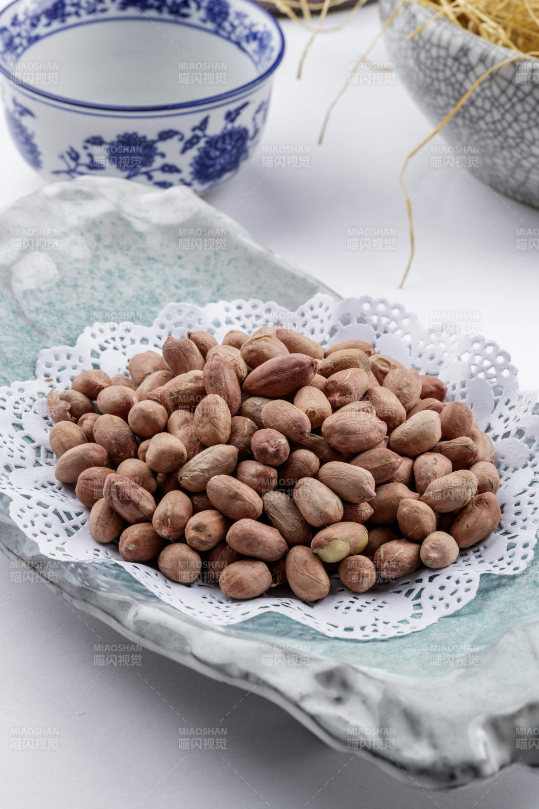 青瓷盘装的有机花生米摆放在白色背景上图片