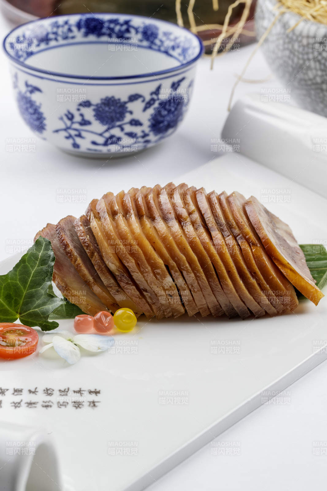 长瓷盘装的烟熏肘花摆放在白色背景上图片