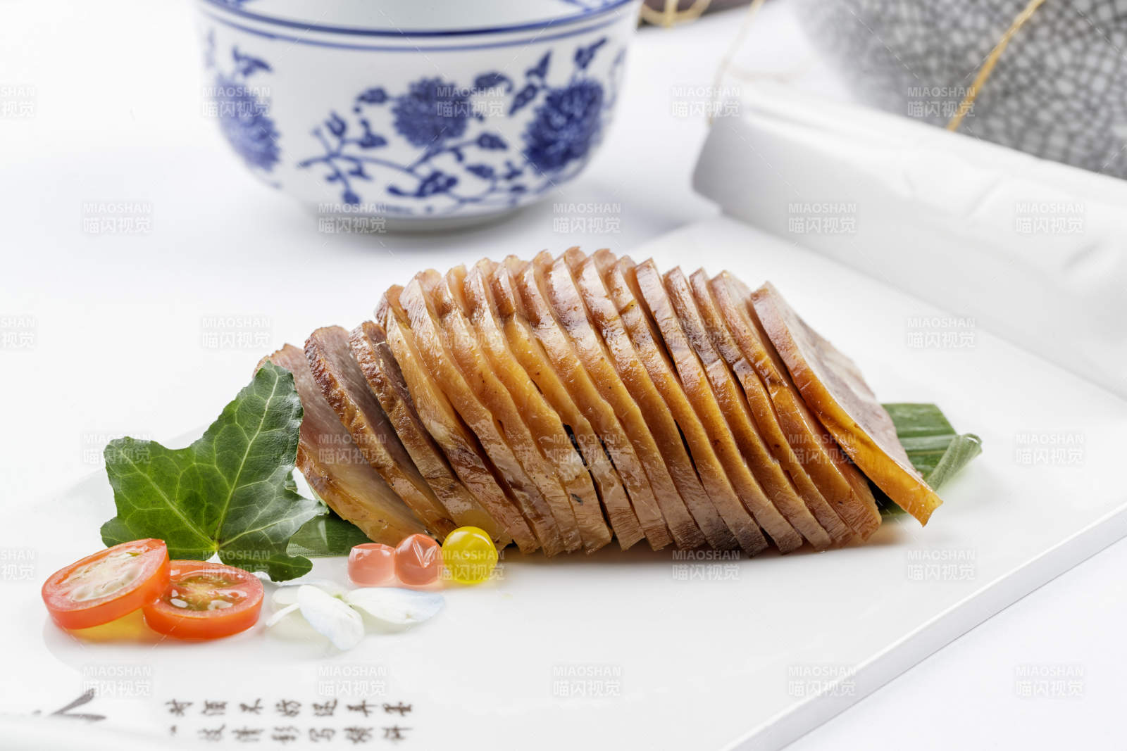 长瓷盘装的烟熏肘花摆放在白色背景上图片