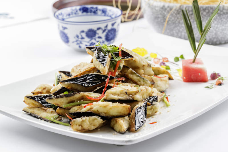 白色瓷盘装的油炸复合味茄子图片