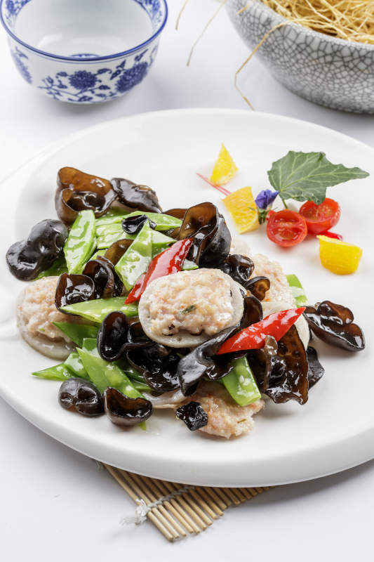 白色圆盘装的荷塘脆玉藕醸摆放在寿司帘上图片