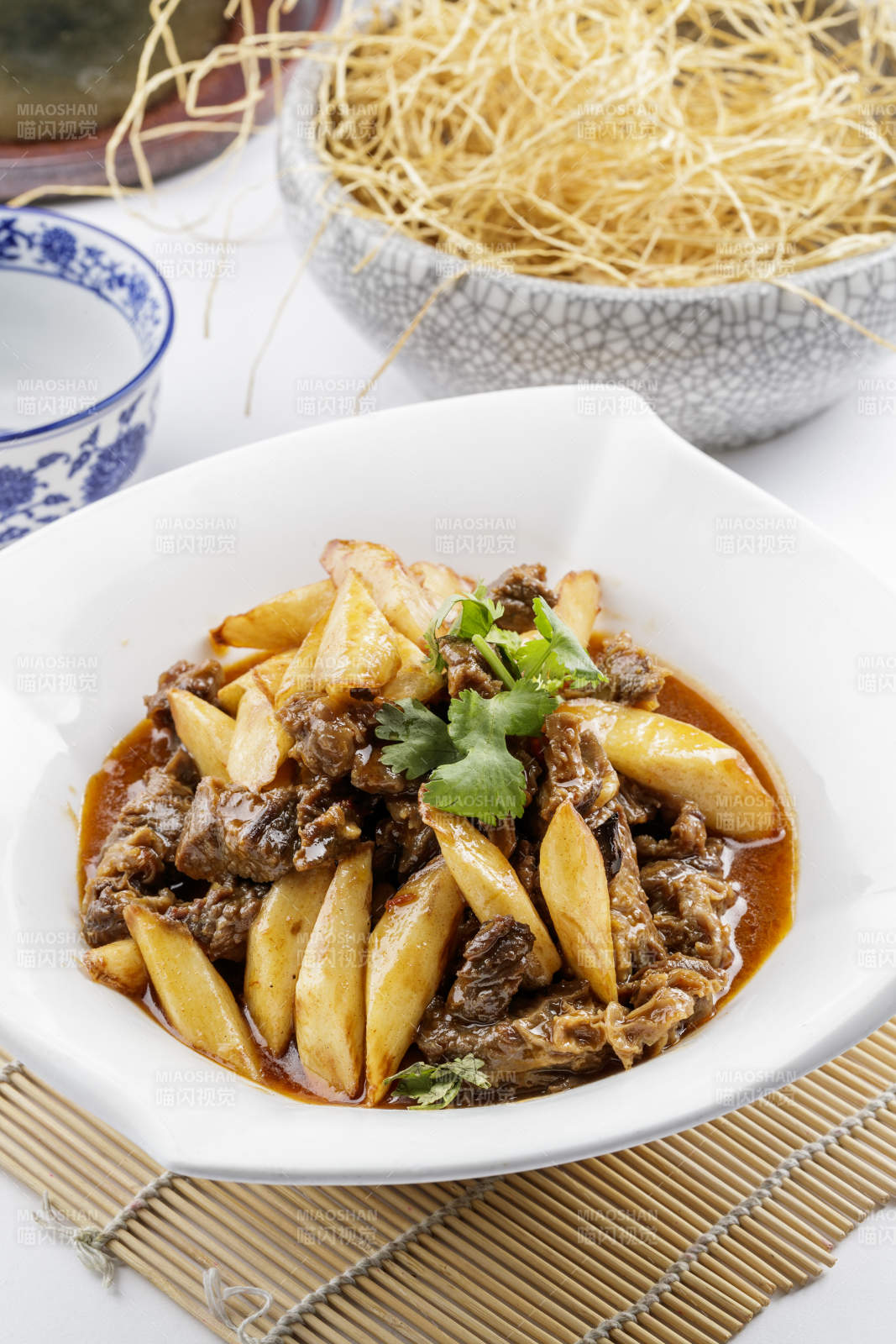 方形瓷盘装的长山药炖牛腩摆放在寿司帘上图片
