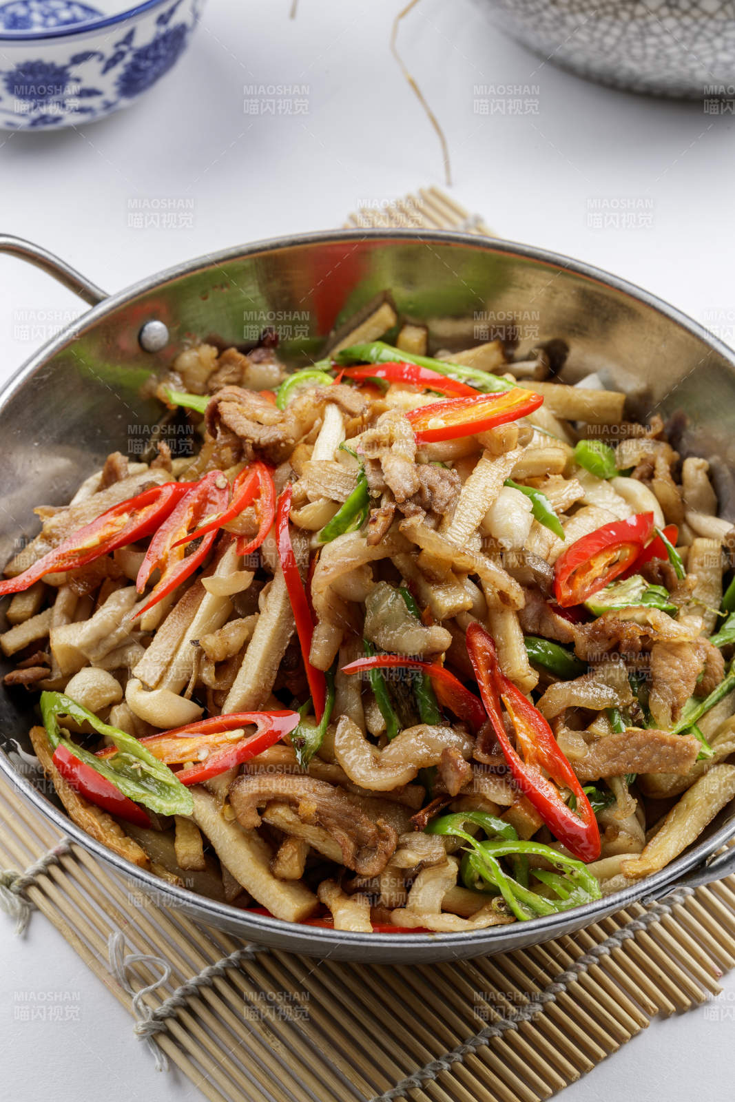 铁锅装的干锅山珍菌摆放在寿司帘上图片