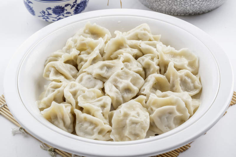 刚出锅的猪肉大葱饺子摆放在白色背景上图片