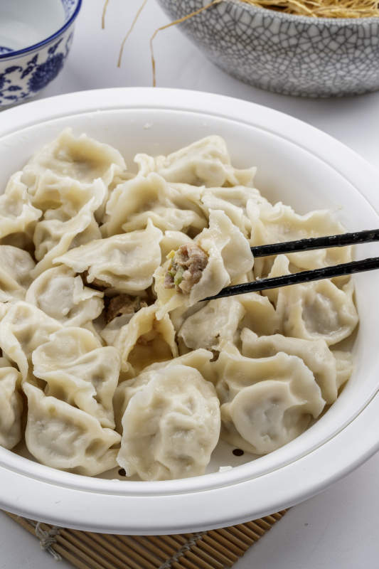 刚出锅的猪肉大葱饺子摆放在白色背景上图片