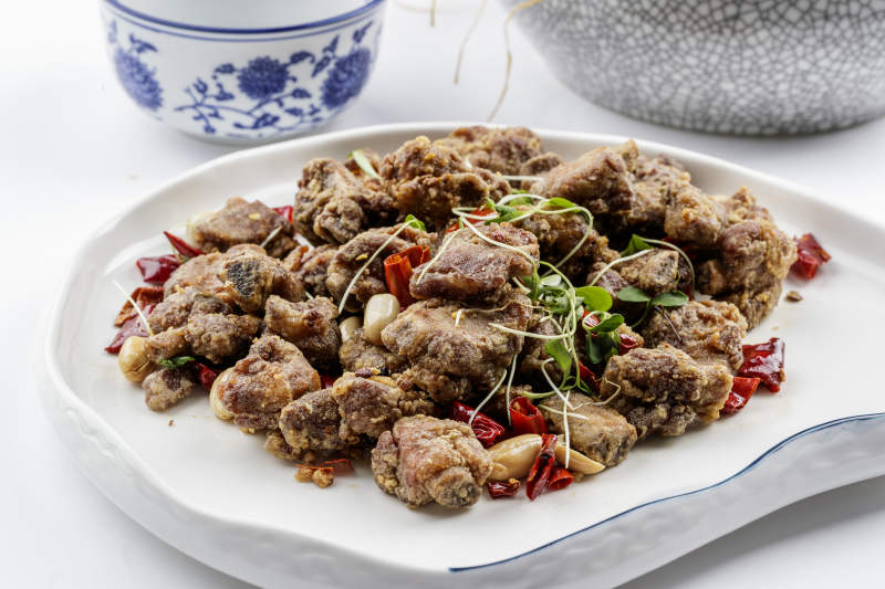 异形瓷盘装的香炸小排骨摆放在白色背景上图片