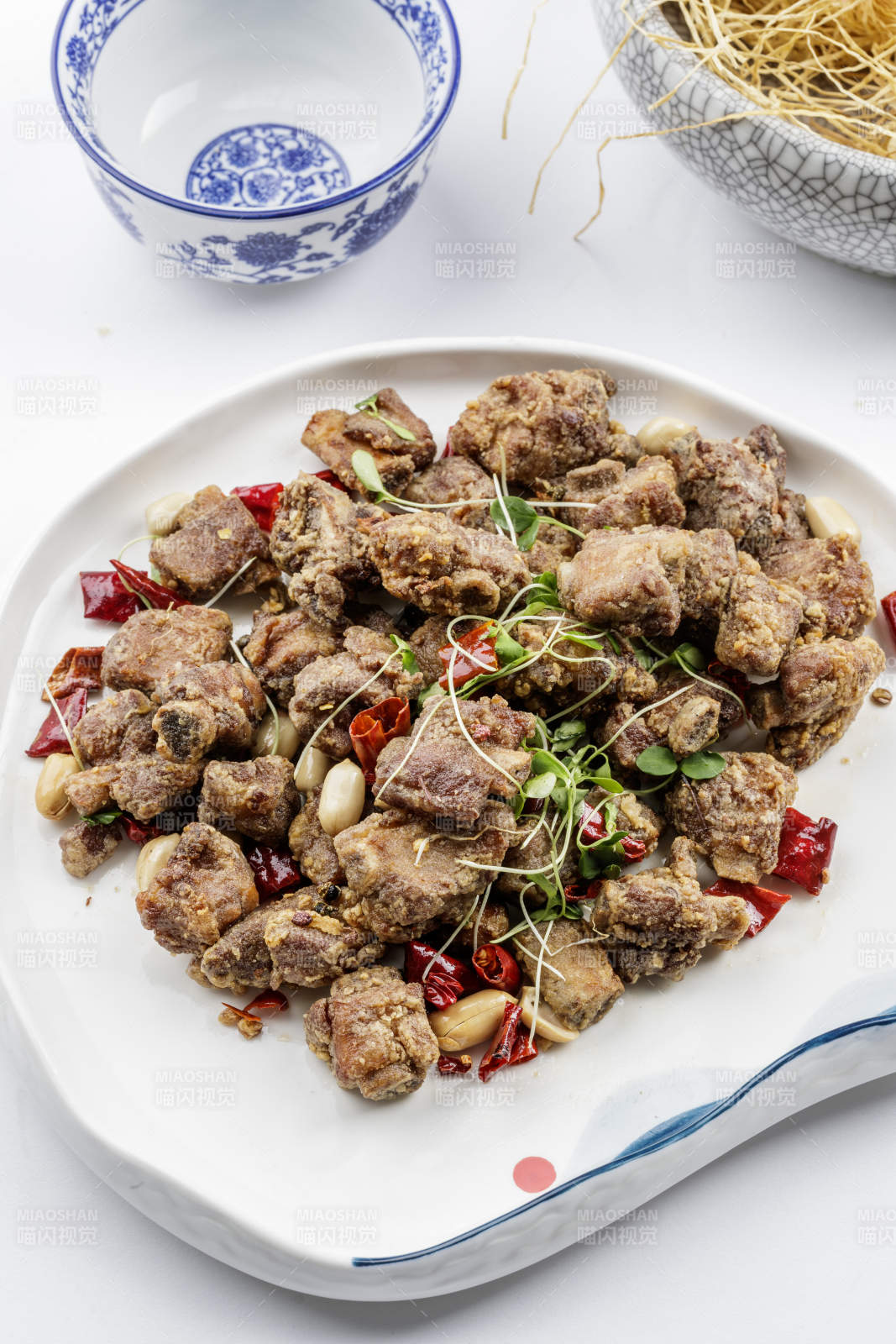 异形瓷盘装的香炸小排骨摆放在白色背景上图片