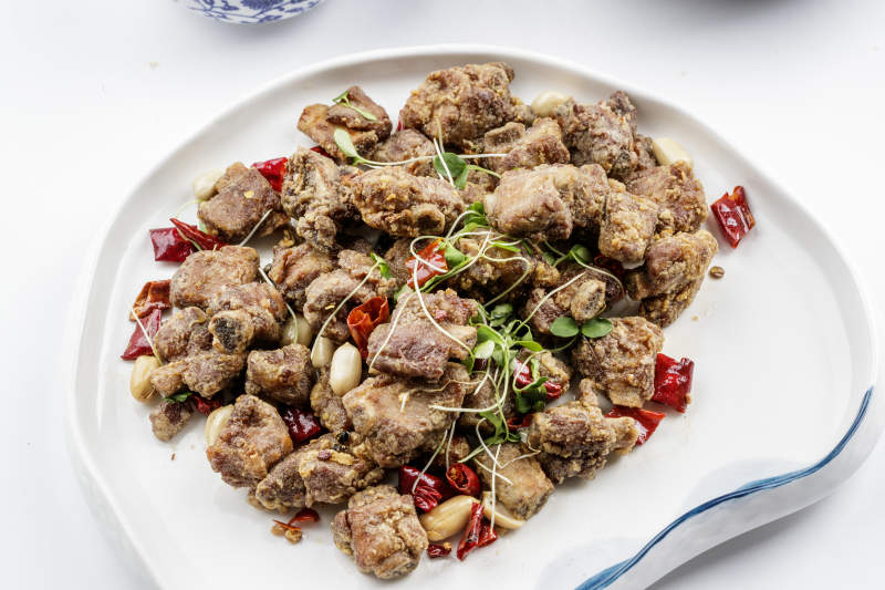 异形瓷盘装的香炸小排骨摆放在白色背景上图片