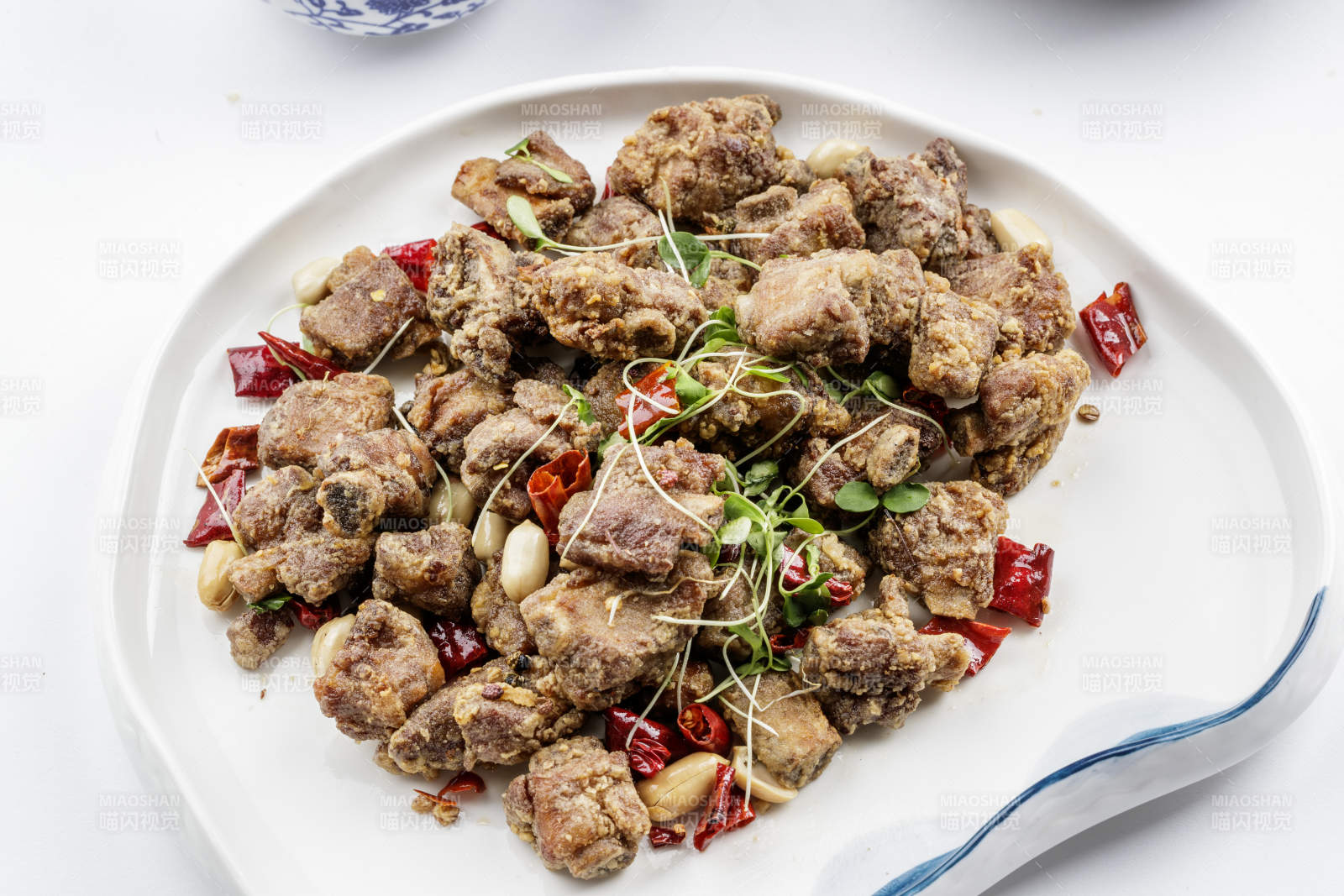 异形瓷盘装的香炸小排骨摆放在白色背景上图片
